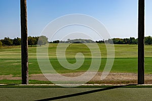 View from a golf driving range tee box flanked by two posts