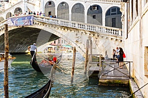 View of gondolas on Grand canal and Ponte di Rialto, many tourists on a bridge