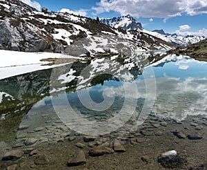 Gorgeous mountain lake in the Alps with reflections and snow remnants