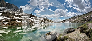 Gorgeous mountain lake in the Alps with reflections and snow remnants