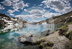 Gorgeous mountain lake in the Alps with reflections and snow remnants