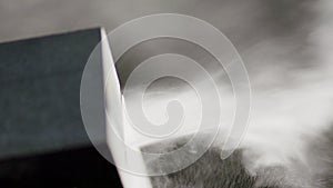 View of grains reflected off stone during circular saw cuts dark granite block.