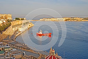 View of Grand Harbour with dome of Our Lady of Liesse church, red ship & Fort Ricasoli in Valletta, Malta