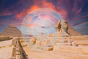 View of the the Great Sphinx and the Pyramids of Giza against a colorful sunset at Giza, Egypt
