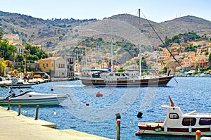 View on Greek sea Symi island harbor port, classical ship yachts, houses on island hills, tourists Aegean Sea bay. Greece islands