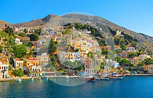 View on Greek sea Symi island harbor port, classical ship yachts, houses on island hills, tourists Aegean Sea bay. Greece islandsV