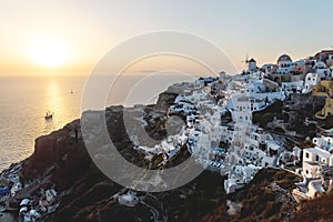 View on Greek village with wind mill during sunset with sail ship, Oia, Santorini, Greece