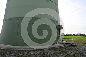 View on green base of round column with door of on-shore wind turbine.