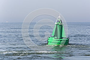 View on a green buoy in the sea, a device to safeguard ships and boats.