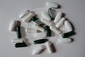 View of green capsules of multivitamins, white caplets of calcium and white capsules of magnesium from above