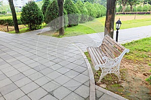 View of green garden with a small square and wooden bench for resing in the corner of the city park