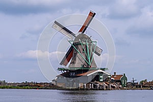 View of a green painted working mill on a river .