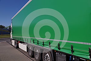 View of the green tarpaulin covering the semi-trailer of the truck. Truck transport