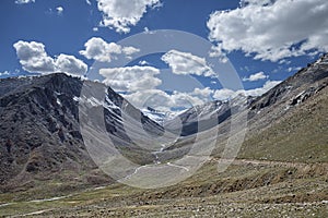 View of green valley with winding river and road and big snowy mountains background