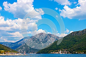 View of green wooded mountains and blue sea, blue sky and white clouds.