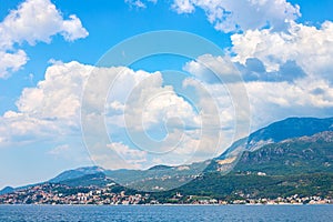 View of green wooded mountains and blue sea, blue sky and white clouds.