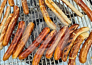 View of a grill with many sausages and meat that are turned regularly
