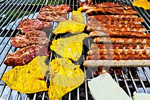 View of a grill with many sausages and meat that are turned regularly