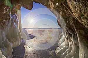 The view from the grotto with icicles, chunks of ice and hummocks to the sun and blye sky. Natural background.