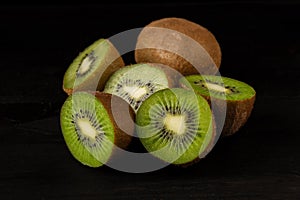 View of a group of open green kiwis on a black background, horizontally