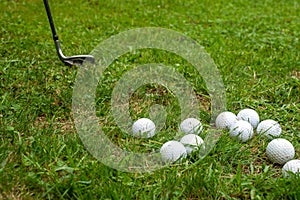 View of a group of white golf balls and golf club background on green grass, horizontally,