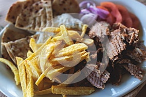 View of Gyros on a plate - traditional greek cuisine dish with kebab meat and pita bread with french fries and tzatziki sauce