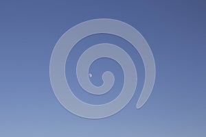 View of half moon with clear blue sky background.