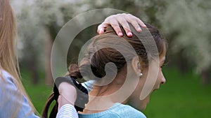 View hands of little girl playing with tying up girlfriend hair in a plait or braid, lifestyle friendly relations