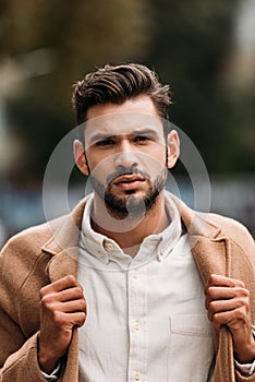 View of handsome bearded man in stylish coat in autumn day on street