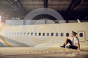 View of handsome captain of aircraft enjoying good weather in the open aviation hangar