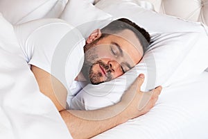 View of handsome smiling man  sleeping in his bed at home