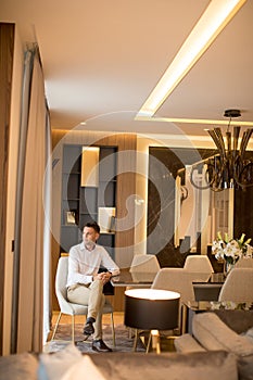 View at handsome welldressed man sitting  in luxury house interior