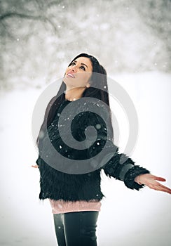 View of happy brunette girl playing with snow in winter landscape. Beautiful young female on winter background. Attractive woman