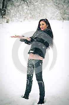 View of happy brunette girl playing with snow in winter landscape. Beautiful young female on winter background. Attractive woman