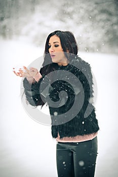 View of happy brunette girl playing with snow in winter landscape. Beautiful young female on winter background. Attractive woman