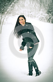 View of happy brunette girl playing with snow in winter landscape. Beautiful young female on winter background. Attractive woman