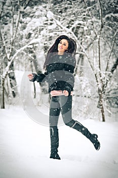 View of happy brunette girl playing with snow in winter landscape. Beautiful young female on winter background. Attractive woman