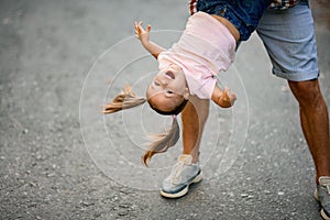 View of happy girl which her father hold upside down and swing her