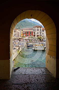 View of the harbor of Malcesine through the arch of an arcade