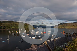 View of the harbour in the town of Portree with boats in the bay and a cruise ship leaving the harbour, in the Island of Skye, Sco