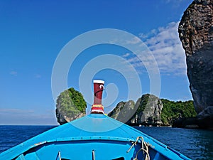 View from the head of wooden long tail boat sailing to the island with beautiful blue sky and cloud from Phi Phi Island ,Thailand