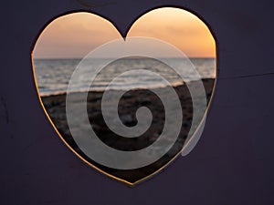 View through heart over people filming at the seaside