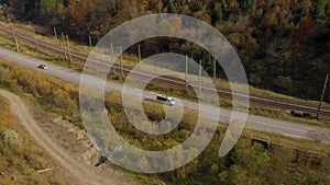 View from the height on the autumn landscape - river, railway, forest on a mountainside, cars on the road