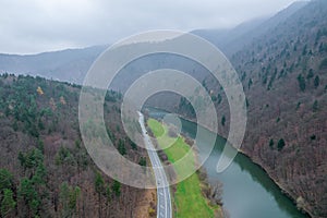 A view from a height of the mountains and the forest, the road in the mountains, the river near road. Fog in mountains.