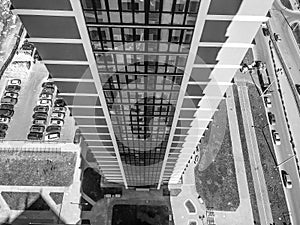 The view from the height of the roof of a tall large building of a skyscraper house on the courtyard with cars opposite