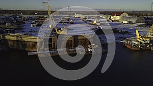 View from a helicopter. Clip. Parking of cargo ships in the river in winter near factories.