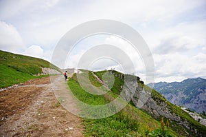 View of high hill and footpath with a walking person on an Alp mountain