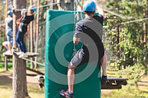 View of high ropes course, process of climbing in amusement acitivity rope park, passing obstacles and zip line on heights in