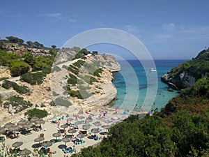 View from the high shore to the sandy beach in the bay of Cala Antena