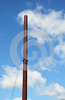 A view of a high vertical flue gas stack, smoke tower, chimney stack, flue gas cooling tower against the clear blue sky